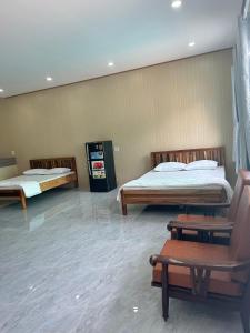 Habitación con 2 camas y una silla. en Motel Khánh Võ en Long Khanh