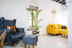 a living room with two blue chairs and a yellow chair at Pili Pili Kahawa House in Stone Town