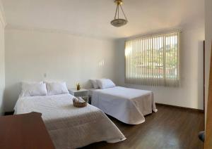 um quarto com 2 camas com lençóis brancos e uma janela em Casa Pepita em Vilcabamba