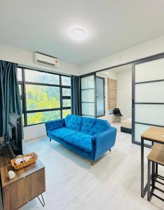 ein blaues Sofa im Wohnzimmer mit Fenstern in der Unterkunft Jesselton Quay by Adara Suites in Kota Kinabalu
