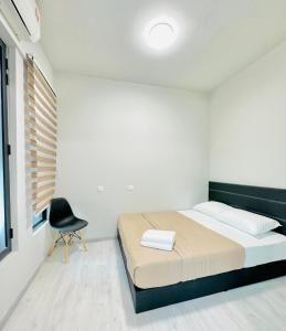 ein Schlafzimmer mit einem Bett und einem Stuhl darin in der Unterkunft Jesselton Quay by Adara Suites in Kota Kinabalu