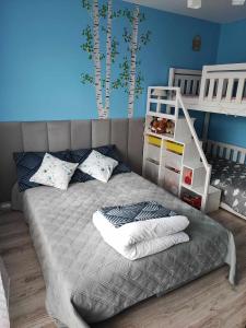 a bedroom with a bed with a ladder and two bunk beds at Apartament W sam Raz in Słupsk