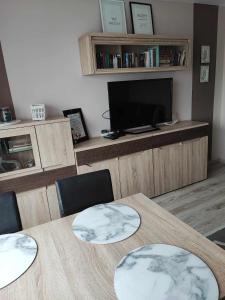 um quarto com uma mesa com cadeiras e uma televisão em Apartament W sam Raz em Słupsk