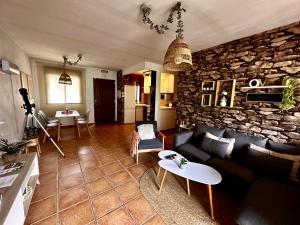 un soggiorno con divano e parete in pietra di Gredos Starlight House a Mijares