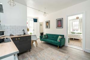 uma cozinha e uma sala de estar com um sofá verde em Shoreditch-bricklane-convenient-central-liverpoolstreet em Londres