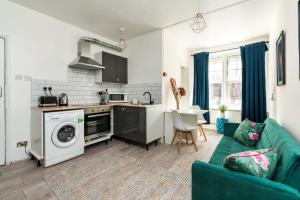 uma cozinha e sala de estar com um sofá verde em Shoreditch-bricklane-convenient-central-liverpoolstreet em Londres