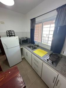a small kitchen with a sink and a refrigerator at Departamento en planta baja con cochera in Salta