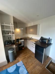 a kitchen with white cabinets and a black counter top at Quiet cosy 1 bedroom apartment Carrington F1 in Nottingham
