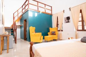 a bedroom with a bed and two yellow chairs at Pili Pili Kahawa House in Stone Town