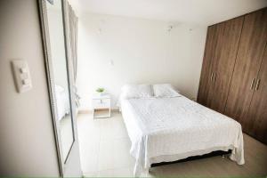 a white bedroom with a bed and a mirror at Espectacular apartamento en excelente sector in Yopal