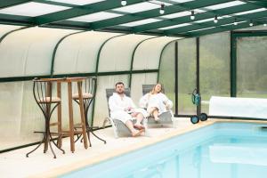 Pompéjac的住宿－L'Escale Sud Gironde - Séjour détente - Calme et nature- Piscine spa sauna massage - Petit-déjeuner sur demande，坐在游泳池旁椅子上的男女