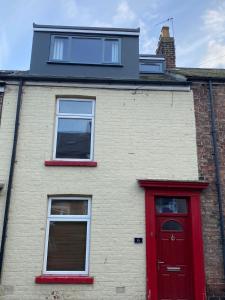 a brick building with a red door and two windows at Nanny and Chips House in Whitby