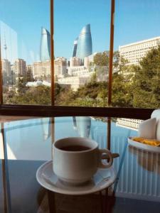 una taza de café sentada en una mesa frente a una ventana en Old City Inn Hotel en Bakú
