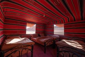 a red room with four beds and a window at Wadi Rum Trail in Wadi Rum