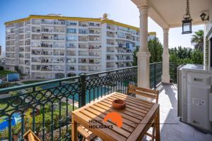 einen Holztisch auf einem Balkon mit einem Gebäude in der Unterkunft #201 City View with Balcony and Pool in Albufeira