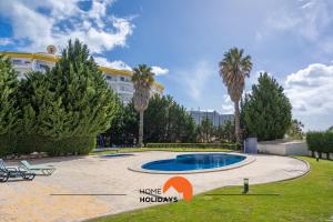 einen Pool in einem Park mit Palmen und einem Gebäude in der Unterkunft #201 City View with Balcony and Pool in Albufeira