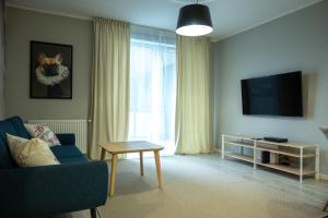 a living room with a blue couch and a television at Apartament na Kaszubach in Kościerzyna