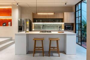 a kitchen with a white counter with two stools at Casa Penta Top Notch Villa in Medellín