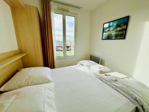ein weißes Bett in einem Zimmer mit Fenster in der Unterkunft PORT ZEN - charme face au port in Rochefort