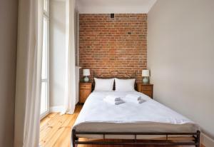 Ce lit se trouve dans une chambre dotée d'un mur en briques. dans l'établissement Koneser Eclectic Apartment, à Varsovie