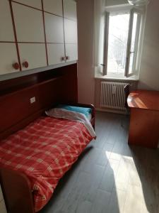 a bedroom with a bed and a desk and a window at Delizioso trilocale Lodi città in Lodi