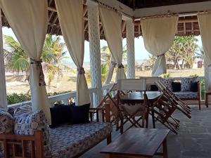 a porch with chairs and a table on the beach at Karibuni Villa - Malindi beach view property in Malindi
