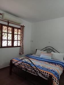 a bedroom with a bed in a room with two windows at Karibuni Villa - Malindi beach view property in Malindi