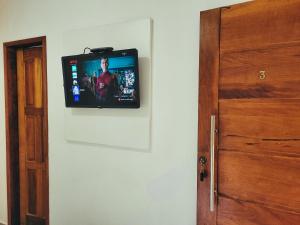 a television on a wall next to a door at News Hospedagem in Paraty