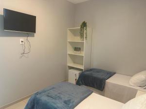 a bedroom with two beds and a tv on the wall at Recanto Catarina in Cascavel