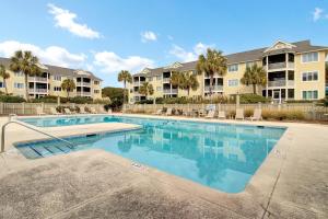 a swimming pool in a apartment complex with palm trees at 204 B Port O Call by AvantStay Beachfront Condo in Isle of Palms