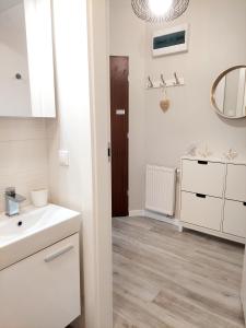 ein Bad mit einem Waschbecken und einem Spiegel in der Unterkunft Apartament Morze Sztuki II, Jantar in Jantar