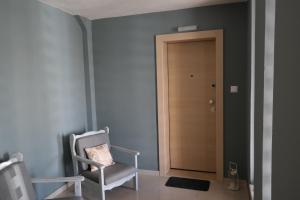 Habitación con silla y puerta de madera. en C&C Apartments, en Alexandroupoli