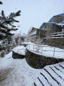 um pátio coberto de neve com um edifício e uma árvore em Chalet Hilltop Kodra e Diellit Popovo Sapka em Tetovo