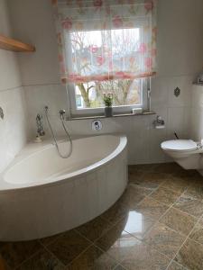 a bathroom with a tub and a toilet and a window at Artgerecht Naturverliebt in Bad Berleburg +16 photos