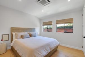 a white bedroom with a large bed and two windows at Villa Castillo 4 in Santa Barbara