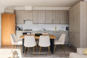 a kitchen with a wooden table and white chairs at The Harlesden Place - Modern 3BDR Flat with Balcony in London