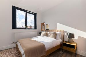 倫敦的住宿－The Harlesden Place - Modern 3BDR Flat with Balcony，一间卧室设有一张大床和一个窗户。