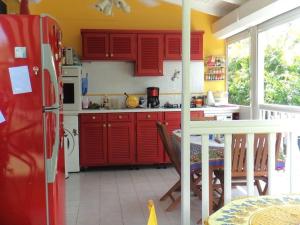 Il comprend une cuisine équipée de placards rouges et d'un réfrigérateur rouge. dans l'établissement villa bougainvillier jardin privatif, à Saint-François