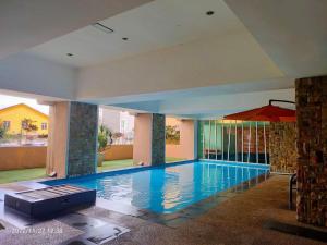 a large swimming pool in a building with an umbrella at De Viana Apartment Homestay in Kota Bharu