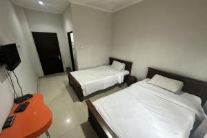 a hotel room with two beds and a television at Hotel Warta Dua in Denpasar
