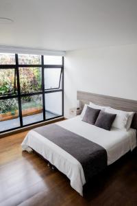 a bedroom with a large bed and a large window at Hotel Piedras De Maní in Manizales