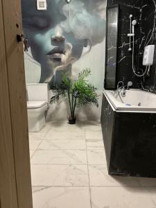 a bathroom with a painting of a woman on the wall at Japandi themed London Apartment in Thornton Heath