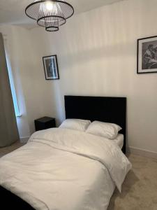 um quarto com uma cama branca e uma cabeceira preta em Japandi themed London Apartment em Thornton Heath