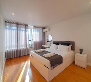 um quarto branco com uma cama grande e um espelho em Porto Soul by Flat in Porto no Porto