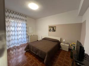 1 dormitorio con 1 cama y TV en LA ROSA DEI VENTI en Villafranca Tirrena