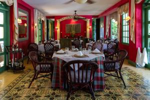 een eetkamer met rode muren en tafels en stoelen bij Hotel Casa Turire in Turrialba