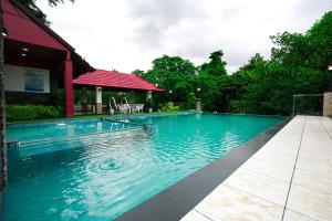 uma piscina com água azul em frente a uma casa em Athirappilly Rainland Resort em Athirappilly