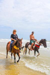 a man and a woman riding horses on the beach at Pousada Sargi&mar in Uruçuca