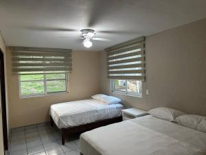 um quarto com 2 camas e 2 janelas em Casa Refugio Eterno em Etzatlán