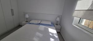 ein weißes Zimmer mit einem Bett und einem Fenster in der Unterkunft Toni Apartment in Sarandë
